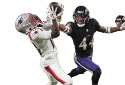 A football player in a Patriots uniform catches a pass while a Ravens defender attempts to block him during a game.
